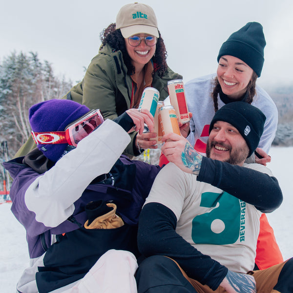 Four people celebrating with drinks on a snowy slope